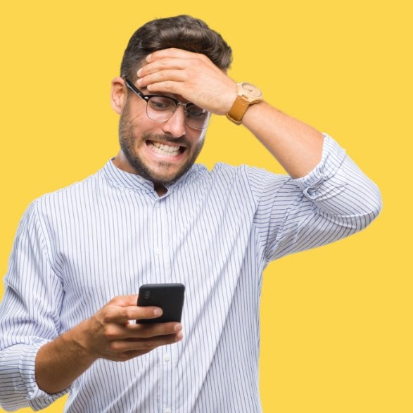 Man grimacing with hand on forehead as he looks at his phone