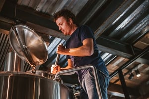A man stirs a vat of beer to brew it to perfection, much in the same way good marketers thoughtfully brew potent content strategies. 