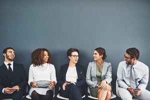 Five smart young job seekers sit next to each other waiting to be interviewed by HR.