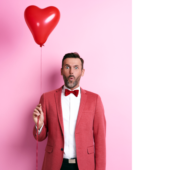 Man in a red suit and bowtie holding a heart-shaped balloon