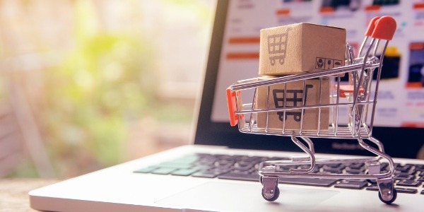 Mini shopping cart on top of a laptop computer