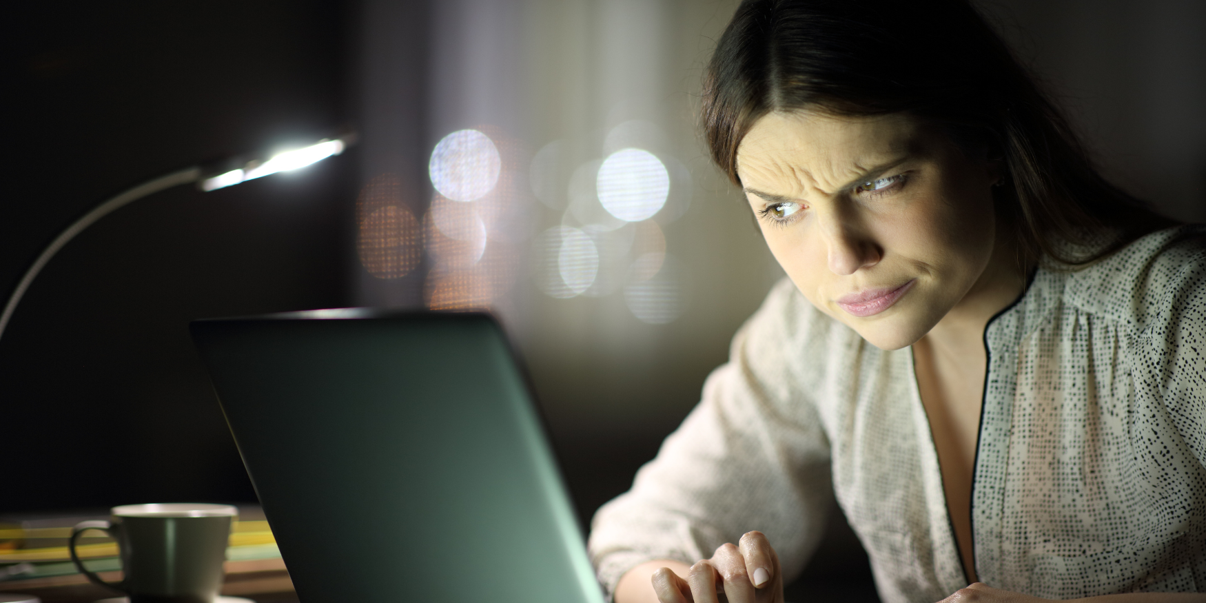 Woman at a desk looking quizzically at her laptop