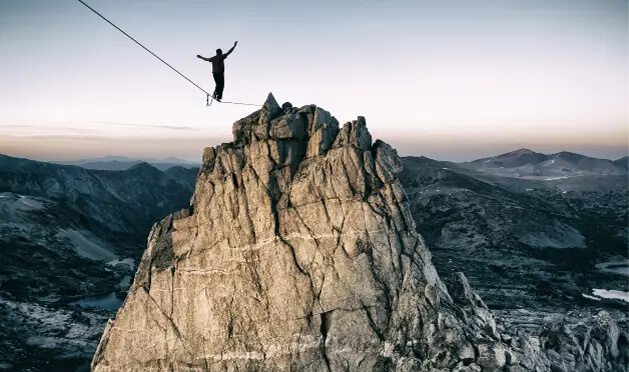 Person on a tightrope in between jagged mountains