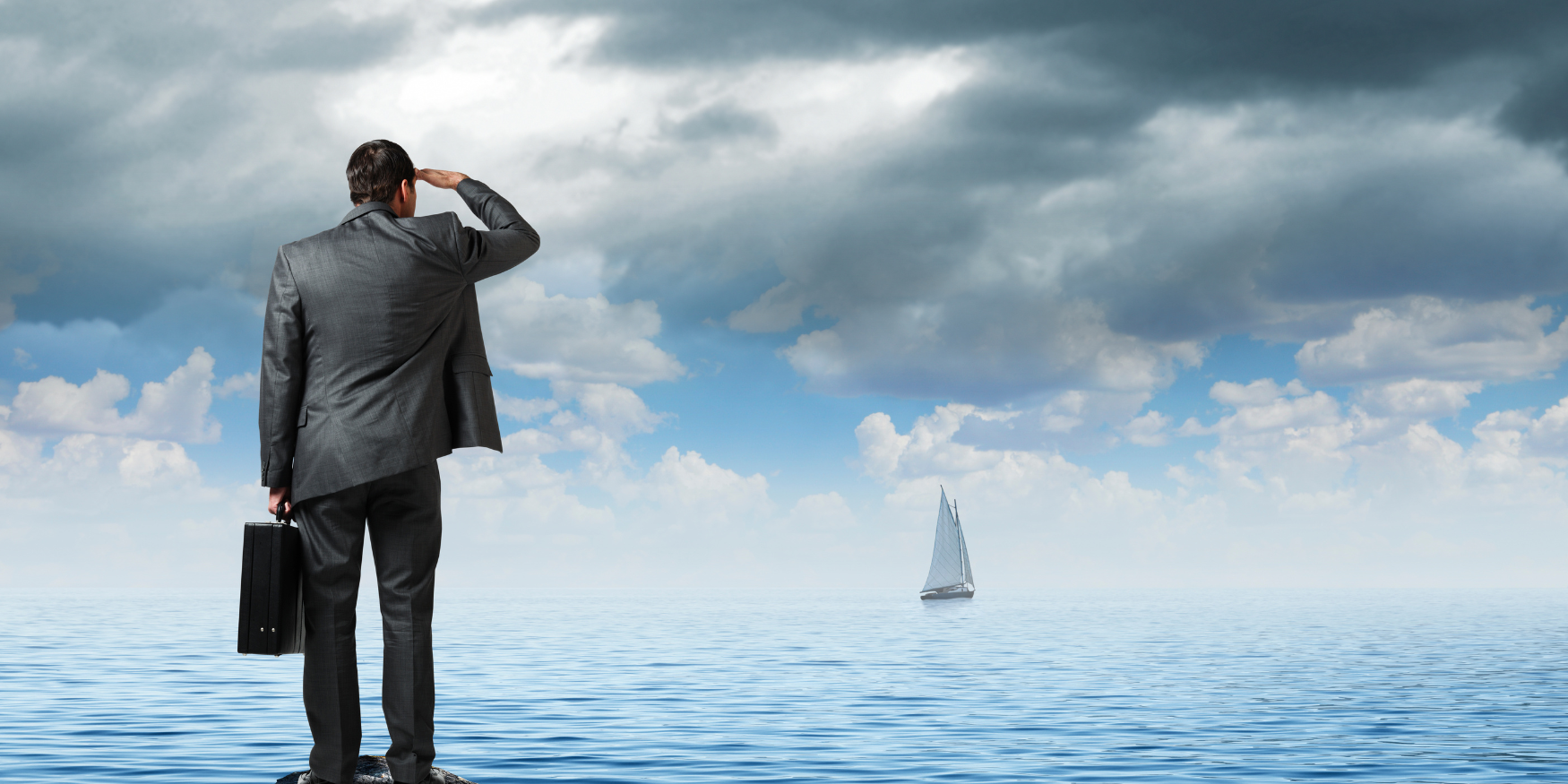 Man in business suit looking out at a boat on the water