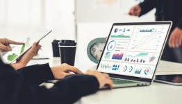 Hands typing at a laptop screen with charts